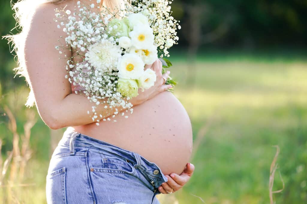A pregnant woman holding a bouquet of flowers.