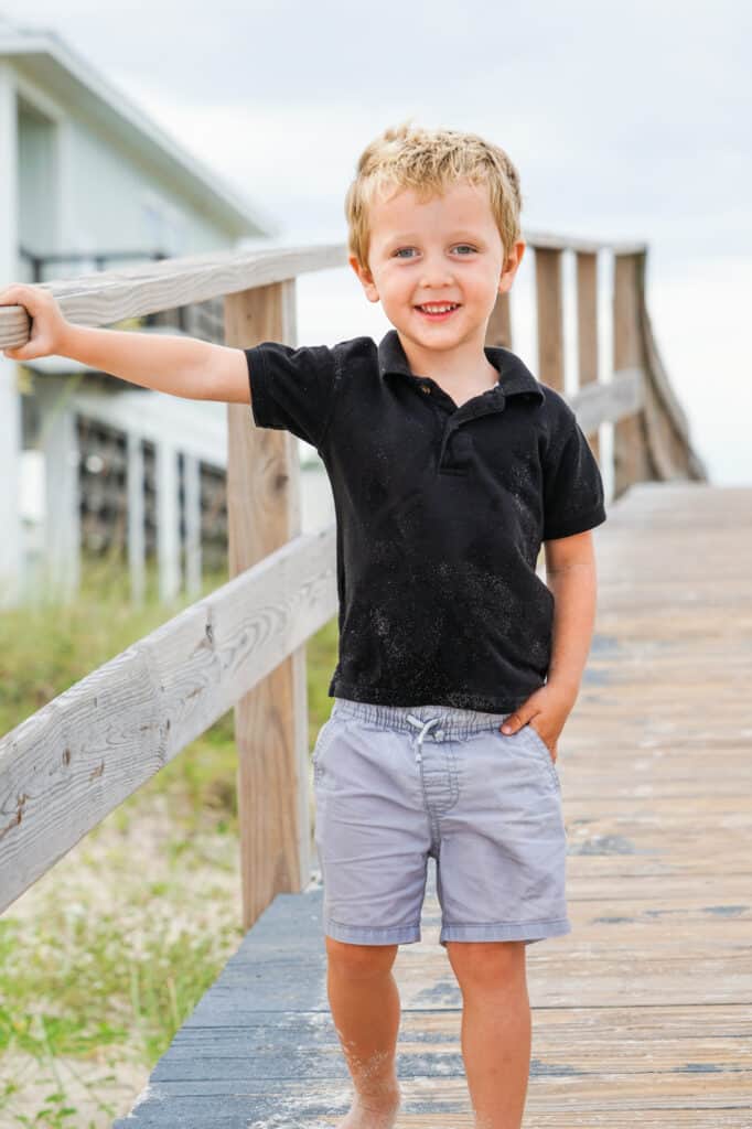 A young boy standing on a wooden boardwalk.