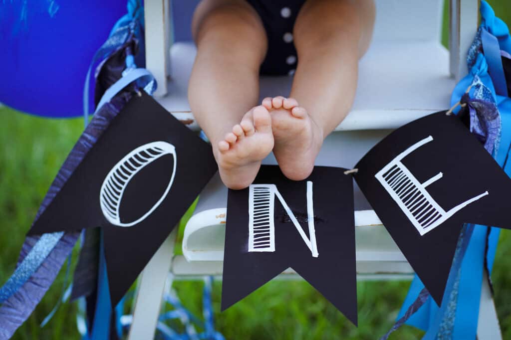 A child's feet on a chair with a blue and black banner.