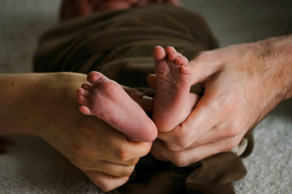 A person is holding a baby's feet.