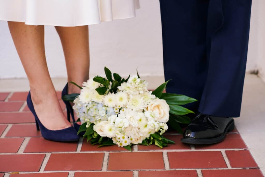 A bride and groom standing next to each other holding a bouquet.