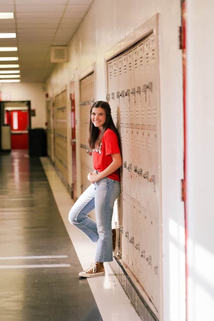 A girl leaning against a locker in a hallway.