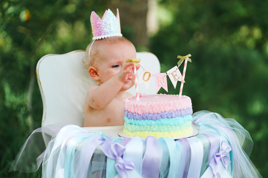 A baby sitting in a high chair eating a cake.