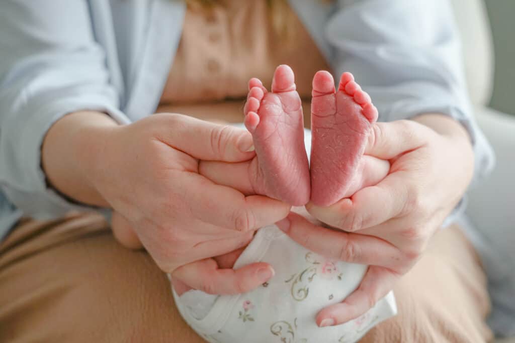 A woman's hands holding a baby's feet.
