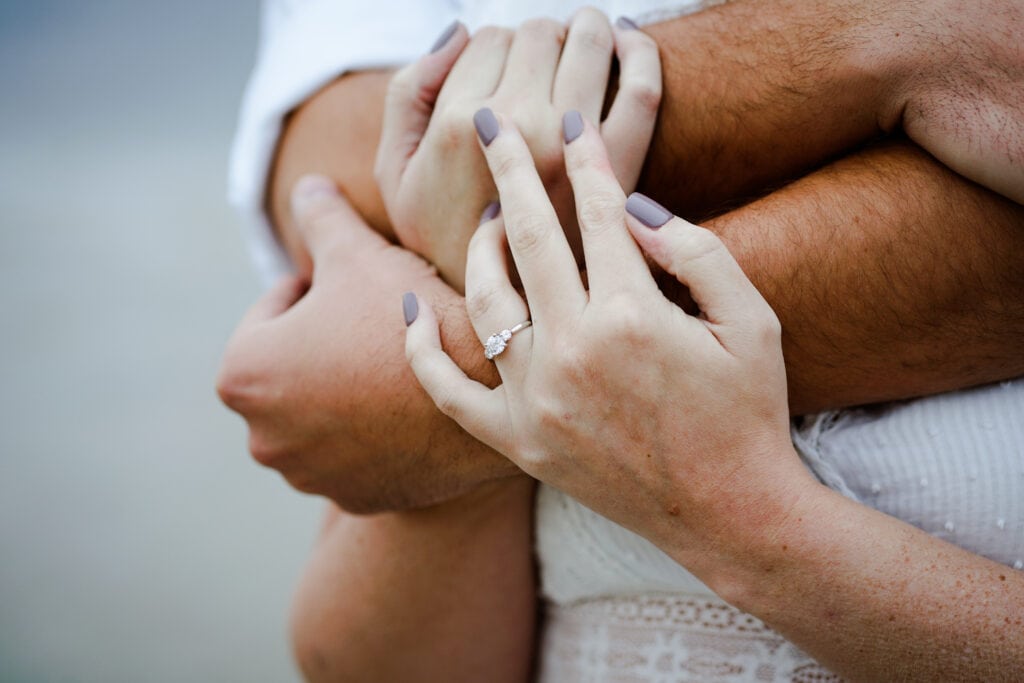 A man and woman hugging each other with rings on their hands.