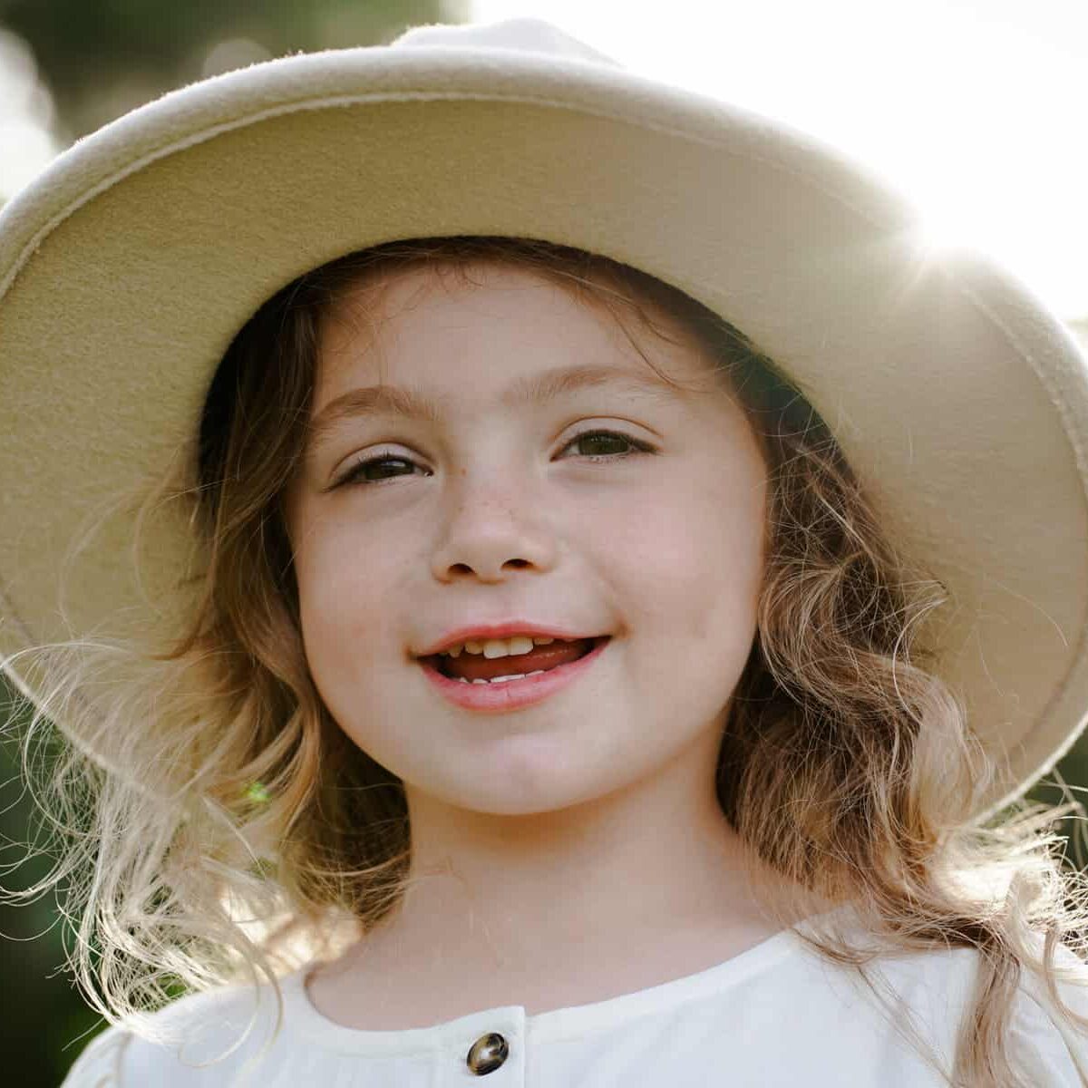 A little girl wearing a white hat.