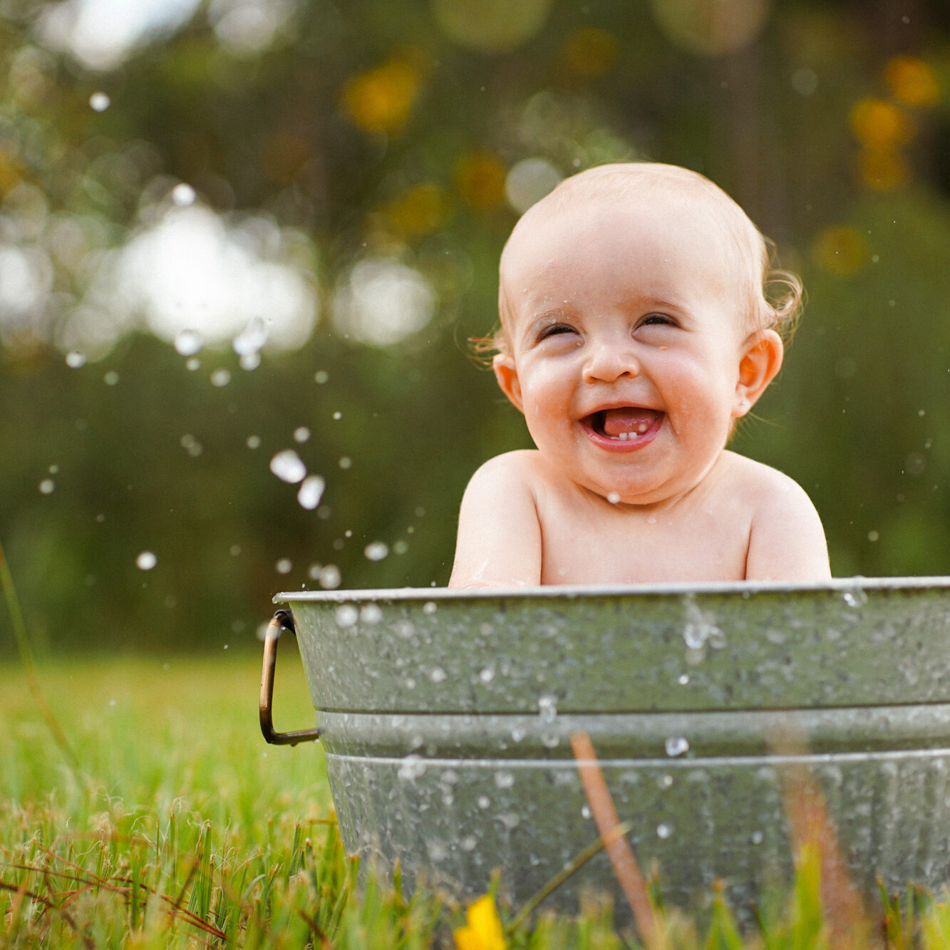 A baby is playing in a bucket of water.